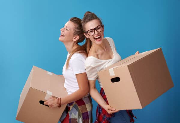 two female college students laughing and holding boxes