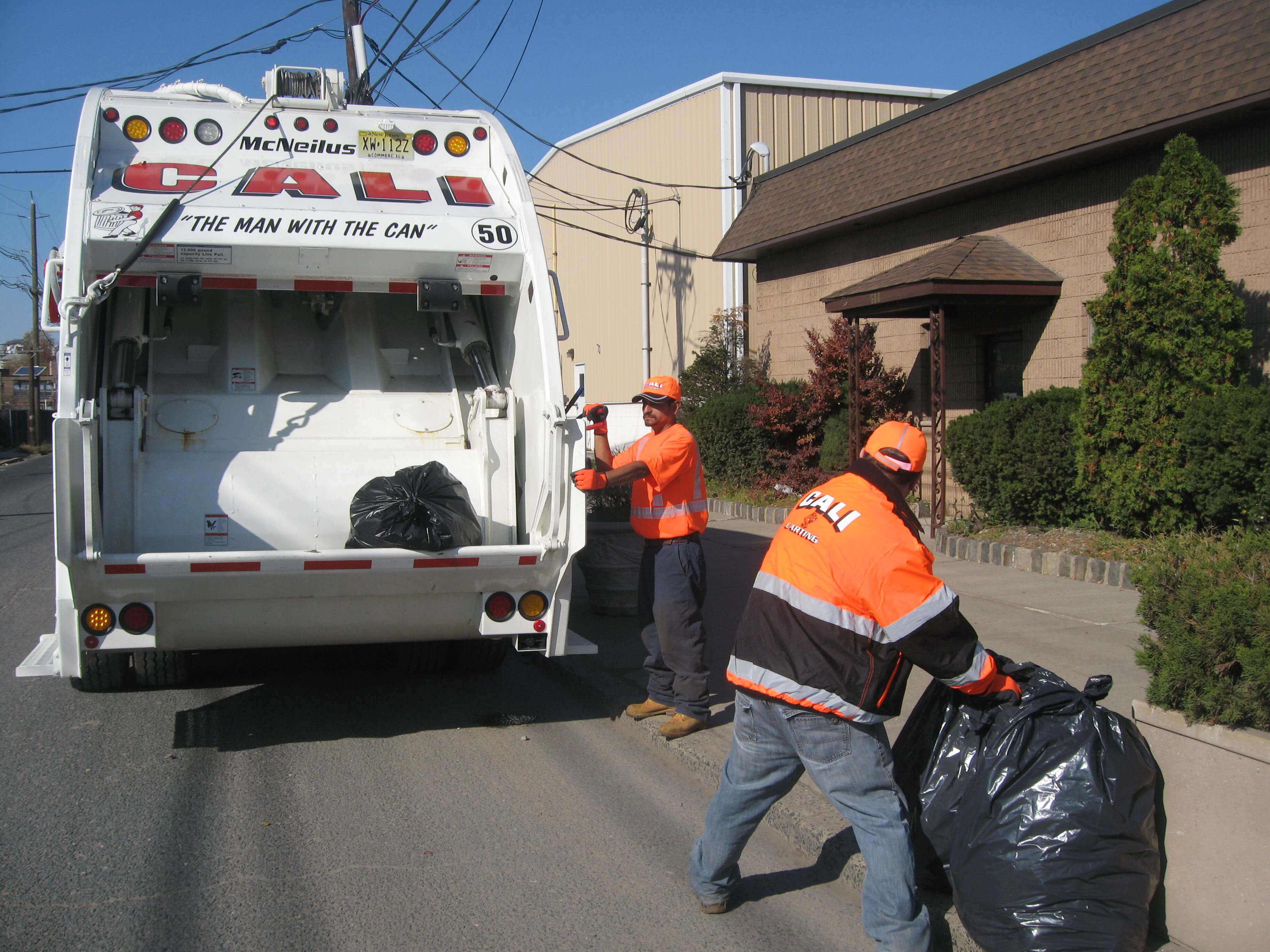 men picking up garbage with white cali carting truck