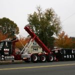 Large black Cali Carting dumpster being delivered in residential neighborhood