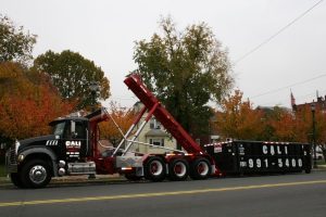 Large black Cali Carting dumpster being delivered in residential neighborhood