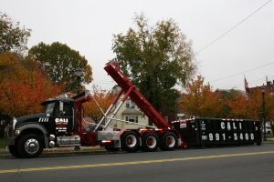 Large black Cali Carting dumpster being delivered in residential neighborhood