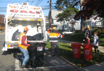 Men filling garbage truck on street